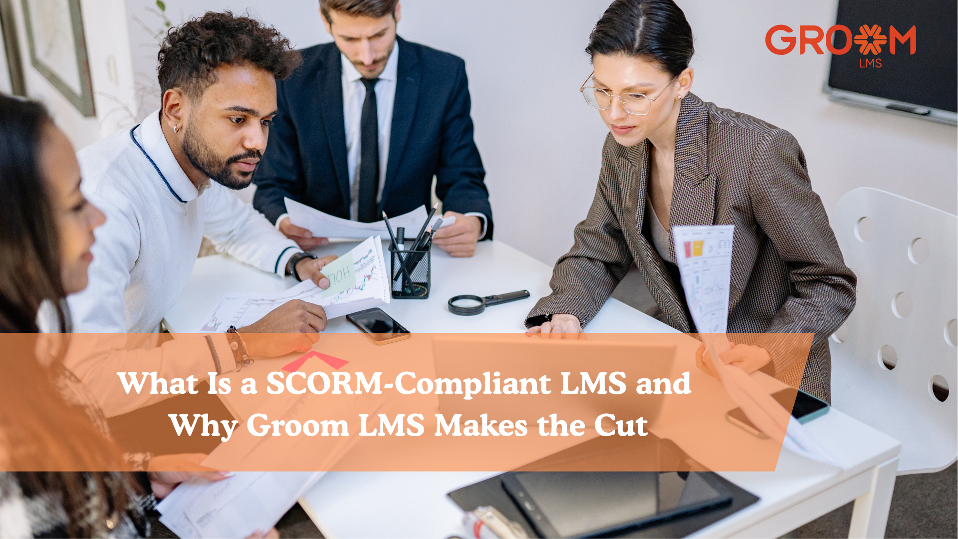 Business professionals collaborating during a team meeting while reviewing reports and discussing learning management strategies for a SCORM-compliant LMS using GroomLMS.