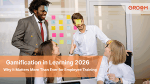 Employees participating in a fun workplace gamification activity during a training session, using sticky notes and interactive challenges to encourage engagement, collaboration, and learning. GroomLMS branding displayed in the top corner.