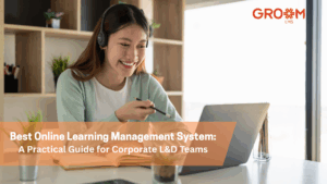 A professional woman wearing a headset participates in an online learning session on her laptop. The image features the GroomLMS logo and the title "Best Online Learning Management System: A Practical Guide for Corporate L&D Teams."
