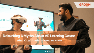 A woman wearing a virtual reality (VR) headset holds VR controllers while participating in an immersive learning experience. A colleague stands beside her with a tablet, smiling and observing the session. The image features the Groom LMS logo and the text: “Debunking 6 Myths About VR Learning Costs: What Organizations Need to Know,” highlighting the use of VR technology in corporate training and e-learning.