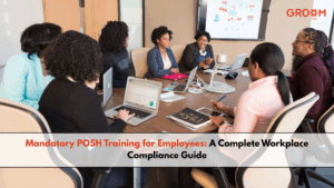 Employees attending a mandatory POSH training session in a conference room with laptops and a presentation on workplace compliance.